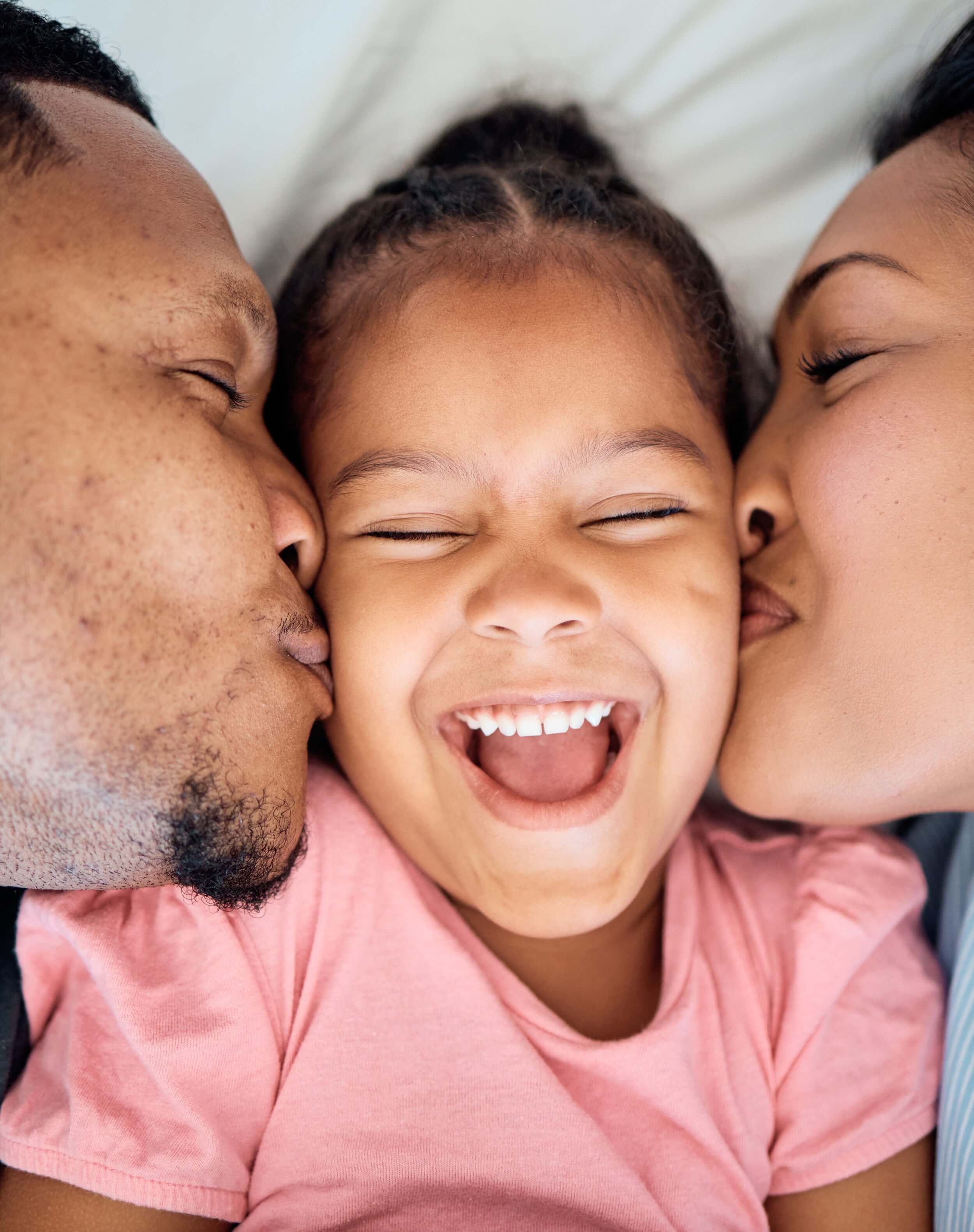 Petite fille souriante entourée de ses parents, symbole de bien-être familial sans dépendance numérique.