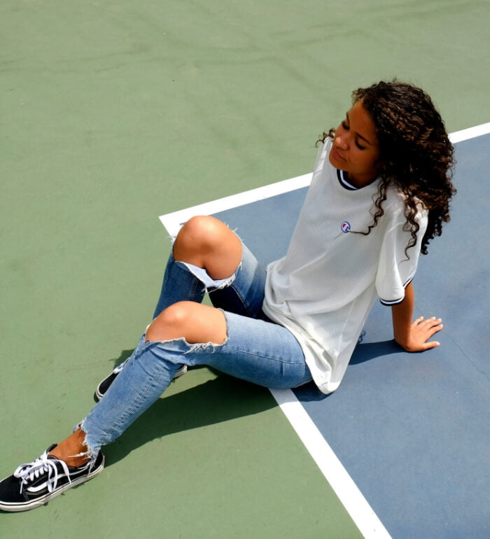 Adolescente détendue assise sur un terrain de sport, illustrant une jeunesse libre et déconnectée